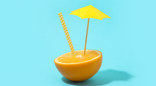 Una cannuccia e un ombrellino decorativo piantati in mezzo a un mezzo arancia