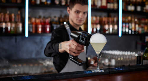 Un barman fait une bulle sur un cocktail à grâce à un smoke gun
