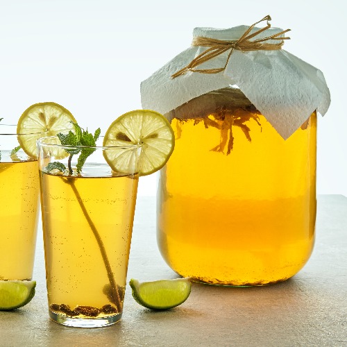 A kombucha jar and two kombucha glasses garnished with mint.