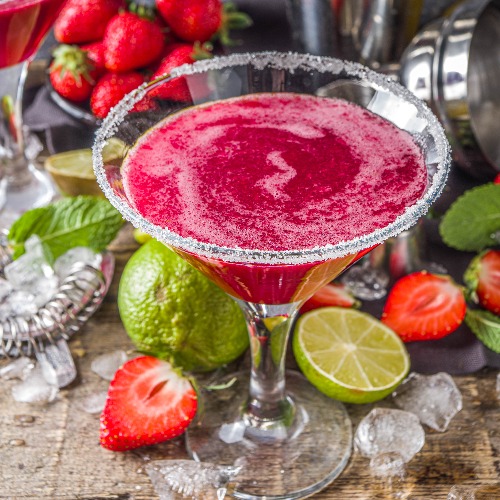 Refrescante bebida alcohólica fría para el verano. Cóctel Daiquiri de fresa con lima, menta y fresa fresca sobre un fondo de madera rústica.