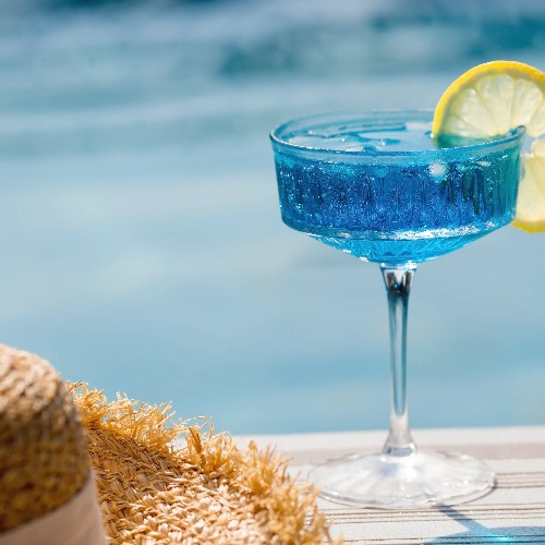 A glass of delicious champagne and curaçao soup with yellow lemons at the bottom of the pool.